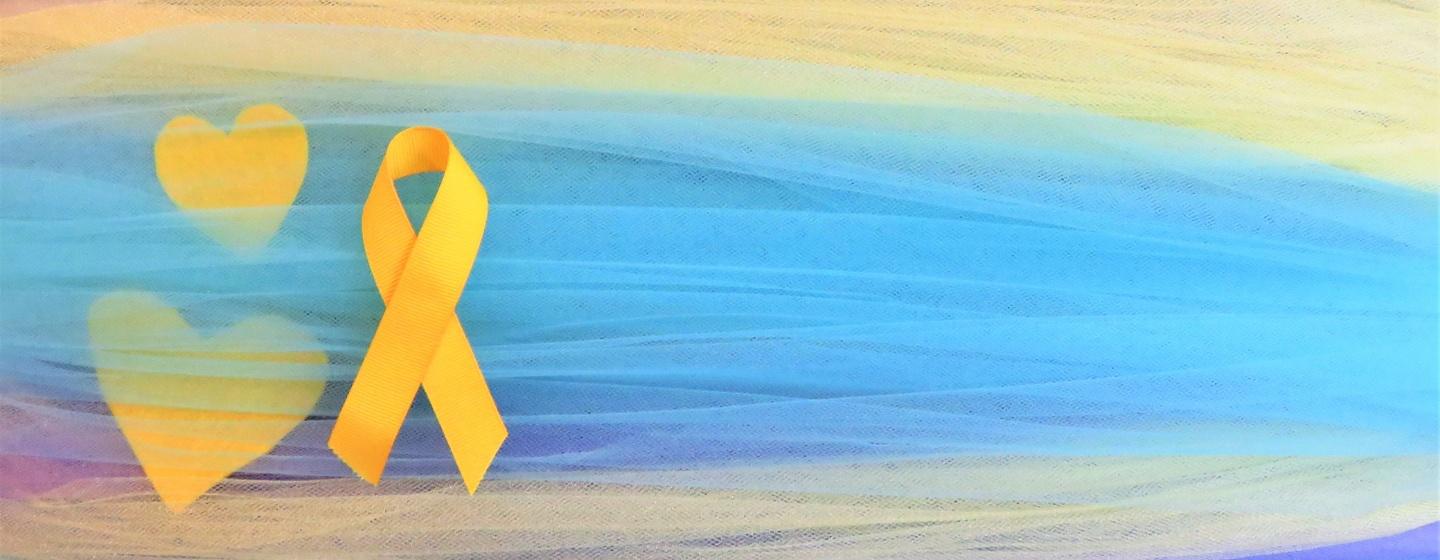 A yellow ribbon symbolizing suicide prevention is shown on a colorful background